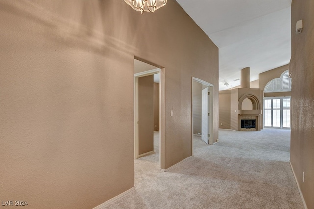 hall with a chandelier, a high ceiling, and light colored carpet