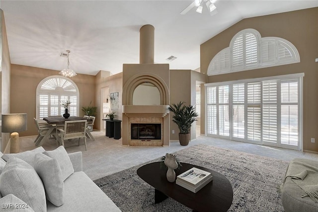 living room featuring ceiling fan with notable chandelier, carpet, and vaulted ceiling