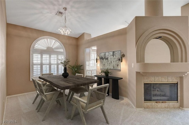 carpeted dining area featuring a tile fireplace and an inviting chandelier