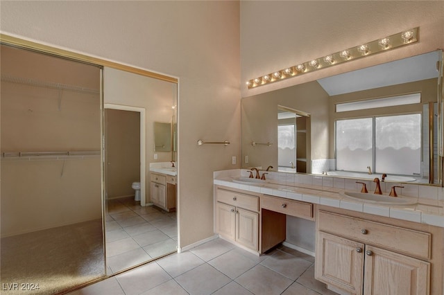 bathroom with tile patterned floors, vanity, vaulted ceiling, and toilet