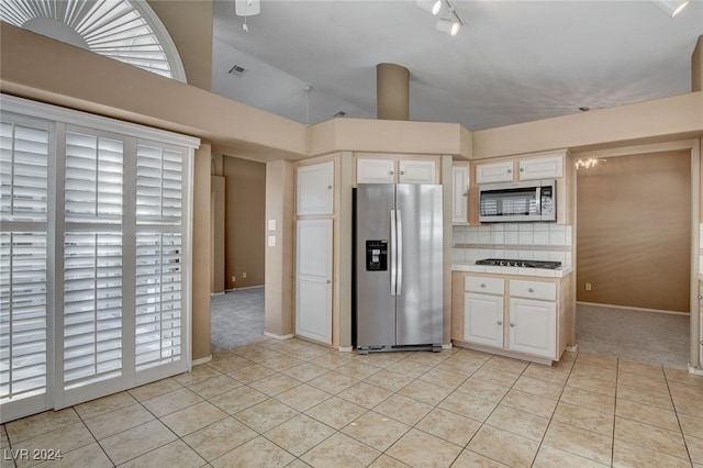 kitchen with tasteful backsplash, white cabinetry, light tile patterned floors, and appliances with stainless steel finishes