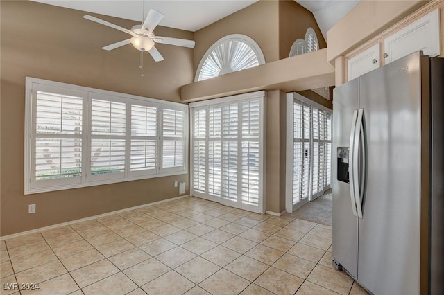 kitchen with stainless steel refrigerator with ice dispenser, vaulted ceiling, ceiling fan, light tile patterned floors, and white cabinets