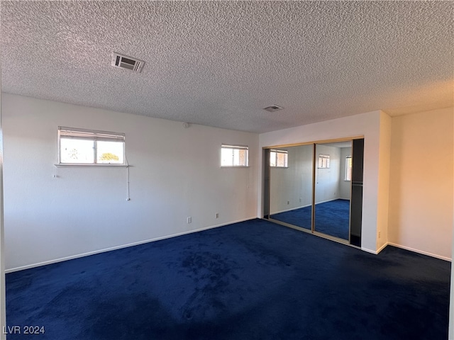 interior space with dark colored carpet and a textured ceiling