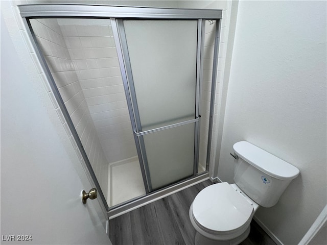 bathroom featuring toilet, hardwood / wood-style floors, and a shower with door