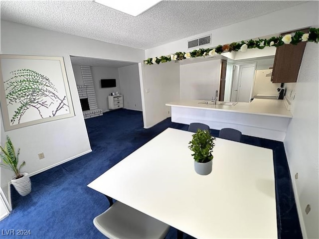 dining room with dark colored carpet, sink, and a textured ceiling