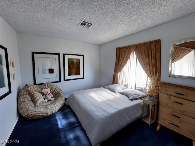 bedroom with a textured ceiling and dark carpet