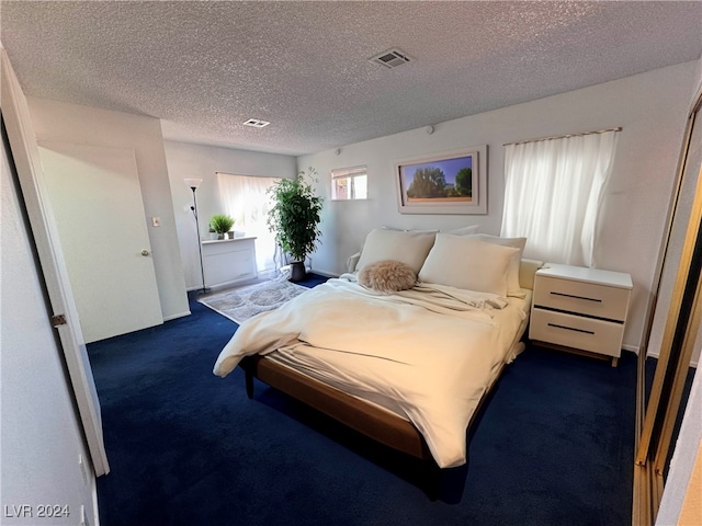 bedroom featuring dark colored carpet and a textured ceiling