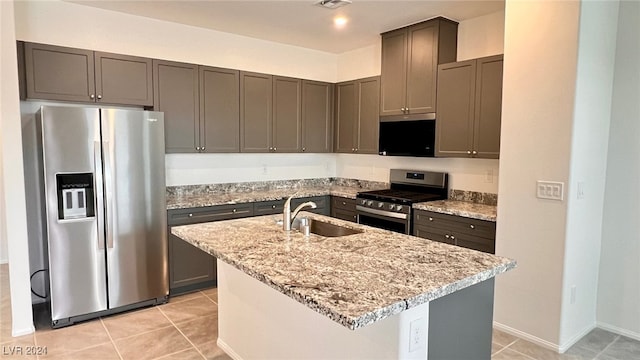 kitchen with a kitchen island with sink, light stone countertops, sink, and appliances with stainless steel finishes