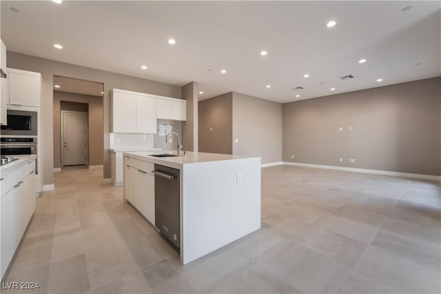 kitchen featuring a kitchen island with sink, sink, light tile patterned floors, appliances with stainless steel finishes, and white cabinetry