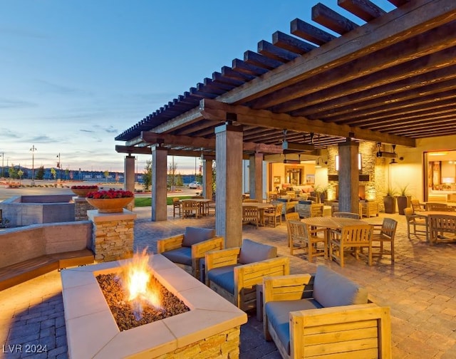 patio terrace at dusk featuring a pergola and an outdoor living space with a fire pit