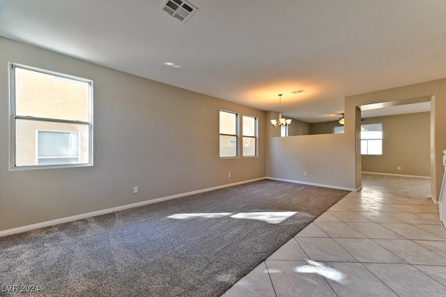 spare room with a wealth of natural light, ceiling fan with notable chandelier, and light tile patterned floors