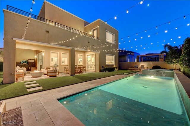 rear view of house with outdoor lounge area, a fenced in pool, and a patio