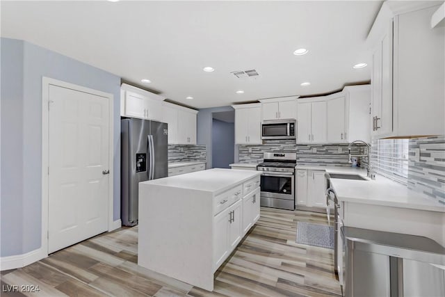 kitchen with a kitchen island, stainless steel appliances, tasteful backsplash, and white cabinetry