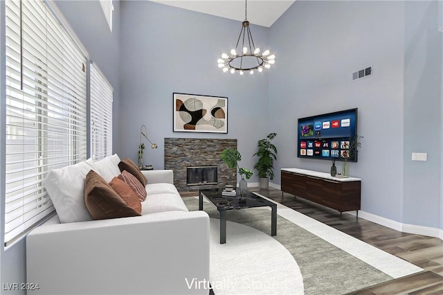 living room with a high ceiling, a fireplace, an inviting chandelier, and hardwood / wood-style floors