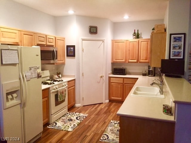 kitchen with light brown cabinets, white appliances, sink, and light hardwood / wood-style flooring