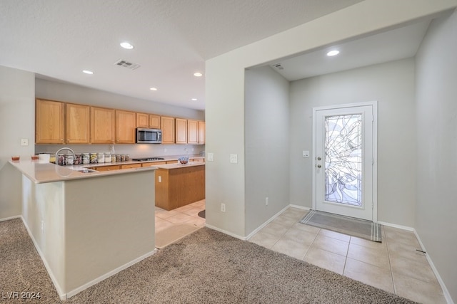 kitchen featuring a textured ceiling, light carpet, kitchen peninsula, and gas cooktop