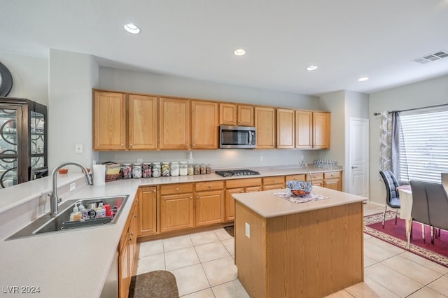 kitchen with a kitchen island, sink, light tile patterned flooring, and stainless steel appliances