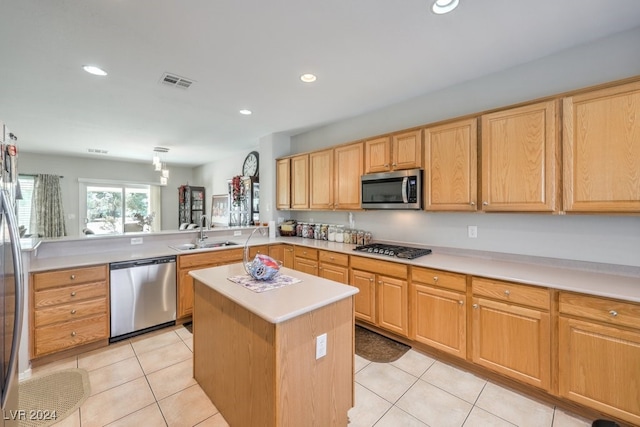 kitchen with stainless steel appliances, a kitchen island, light tile patterned floors, sink, and kitchen peninsula