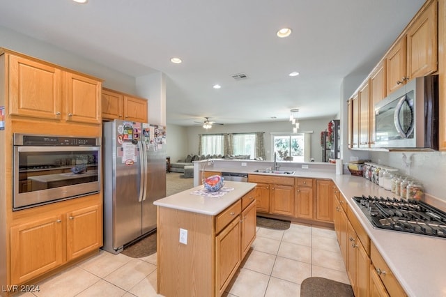 kitchen with appliances with stainless steel finishes, sink, a center island, and light tile patterned flooring