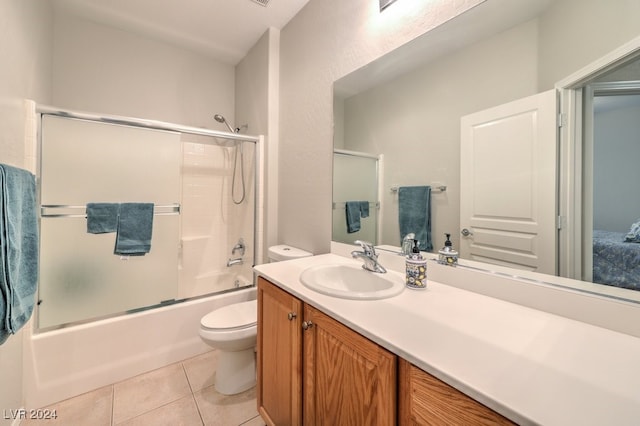 full bathroom with vanity, tile patterned floors, combined bath / shower with glass door, and toilet