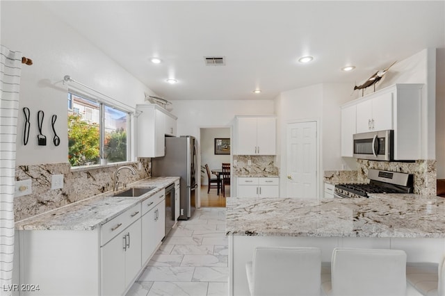 kitchen featuring a kitchen bar, white cabinetry, sink, and appliances with stainless steel finishes