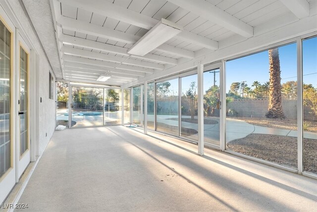 unfurnished sunroom featuring beam ceiling and a wealth of natural light