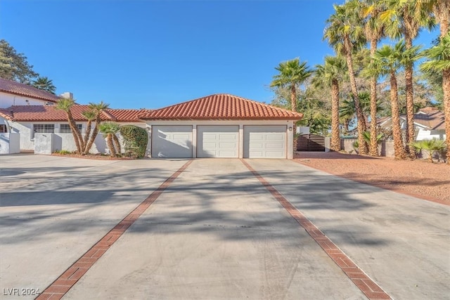 mediterranean / spanish house with concrete driveway, fence, a tile roof, and stucco siding