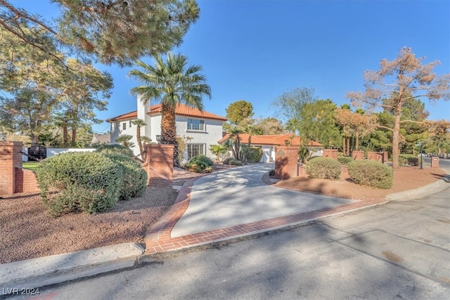 mediterranean / spanish-style house with decorative driveway, fence, and stucco siding