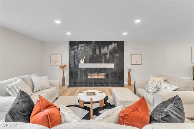 living area featuring light wood finished floors, a tile fireplace, baseboards, and recessed lighting