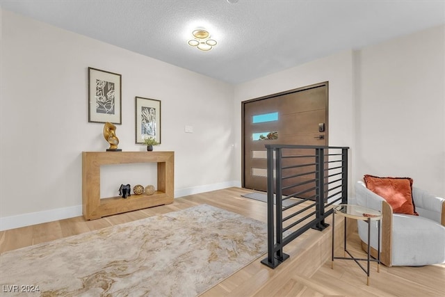 foyer featuring a textured ceiling, baseboards, and wood finished floors