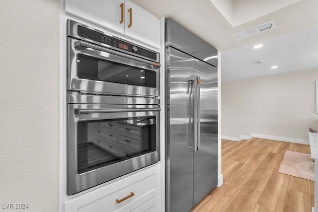 kitchen featuring white cabinets, light wood finished floors, visible vents, and stainless steel appliances