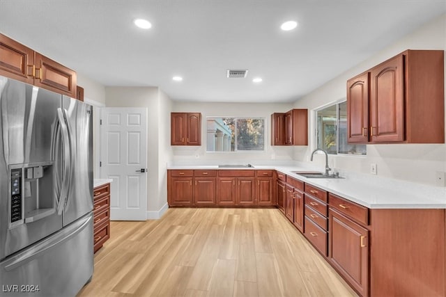 kitchen featuring visible vents, light countertops, light wood-type flooring, stainless steel refrigerator with ice dispenser, and a sink