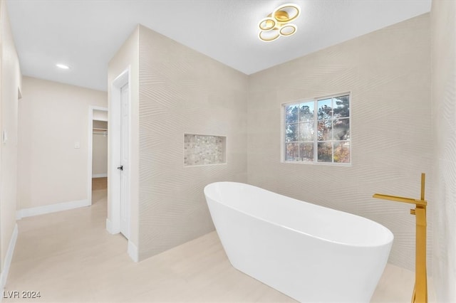 bathroom with a freestanding bath, recessed lighting, and baseboards