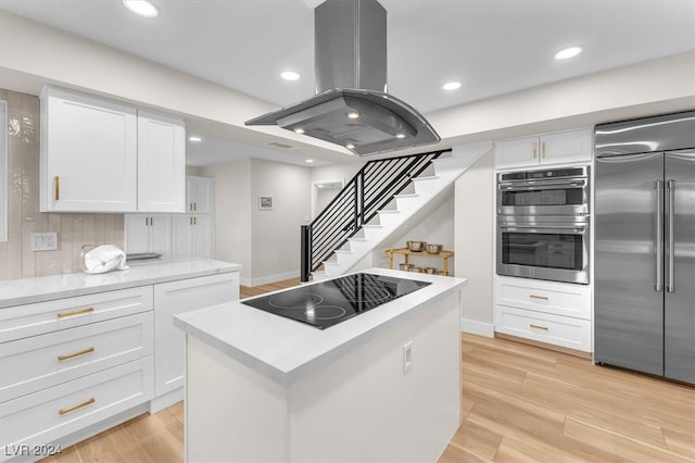 kitchen featuring stainless steel appliances, light countertops, island range hood, and white cabinetry