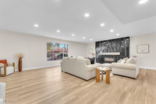 living room featuring baseboards, light wood finished floors, a premium fireplace, and recessed lighting