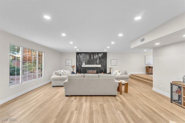 living room with light wood-type flooring, a fireplace, visible vents, and recessed lighting