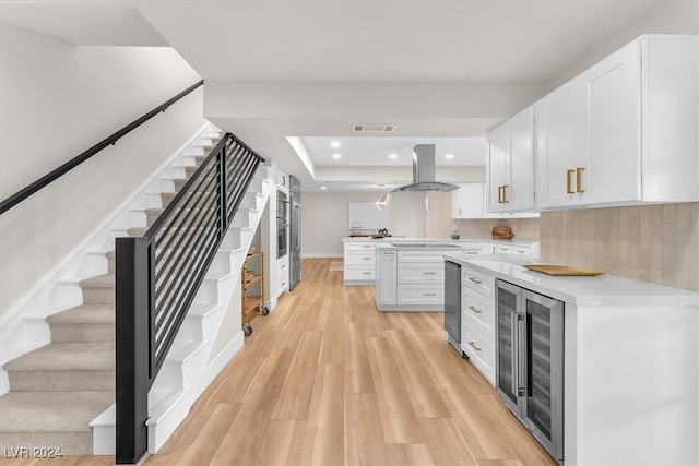 kitchen with wine cooler, island exhaust hood, light countertops, visible vents, and white cabinets