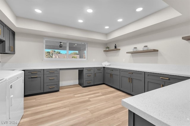 kitchen with light countertops, gray cabinets, built in study area, open shelves, and washer and clothes dryer