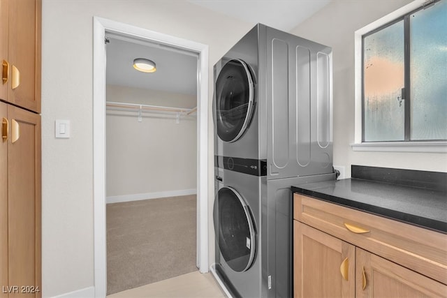 washroom featuring light carpet, cabinet space, and stacked washer / drying machine