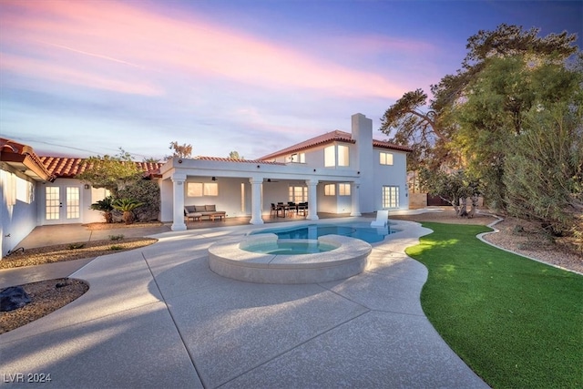 back of house with a patio, a tile roof, a chimney, an outdoor living space, and stucco siding