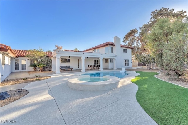 rear view of house with a chimney, an outdoor hangout area, an in ground hot tub, a tiled roof, and a patio area