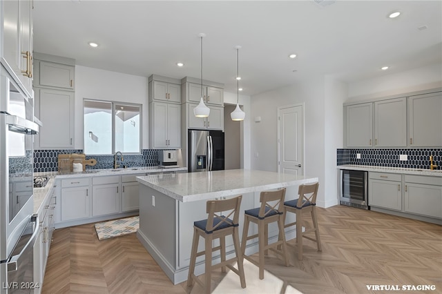 kitchen with wine cooler, light parquet floors, decorative backsplash, a kitchen island, and appliances with stainless steel finishes