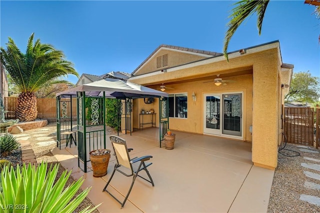 back of property with a fenced backyard, a ceiling fan, a patio, and stucco siding