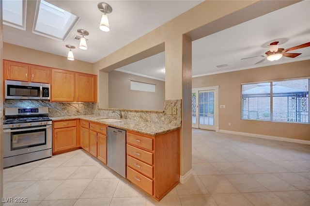 kitchen with stainless steel appliances, a skylight, a sink, ornamental molding, and backsplash