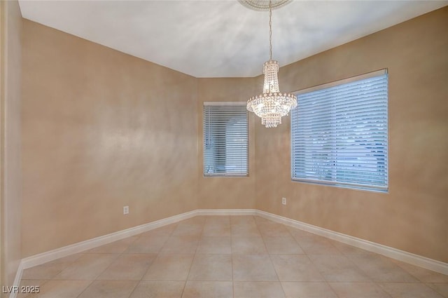 tiled spare room featuring a notable chandelier and baseboards