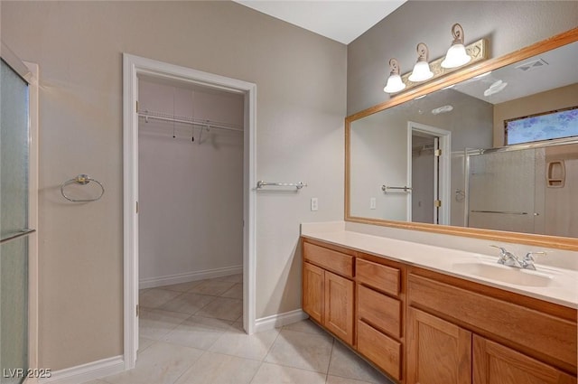 bathroom with a spacious closet, a stall shower, vanity, tile patterned flooring, and baseboards