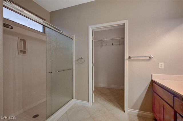 bathroom with a stall shower, tile patterned floors, vanity, and a spacious closet