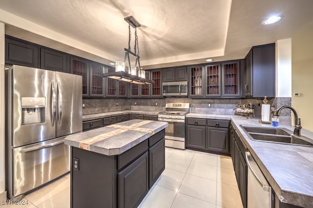 kitchen featuring sink, appliances with stainless steel finishes, backsplash, hanging light fixtures, and a kitchen island