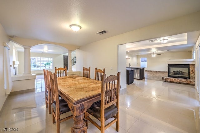 tiled dining room featuring ceiling fan and decorative columns