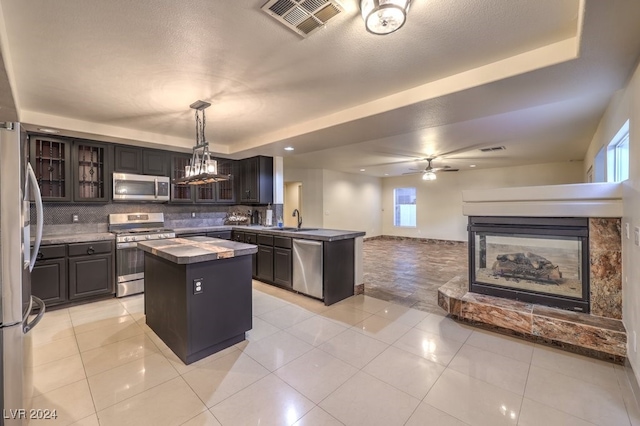 kitchen with sink, appliances with stainless steel finishes, tasteful backsplash, a kitchen island, and pendant lighting